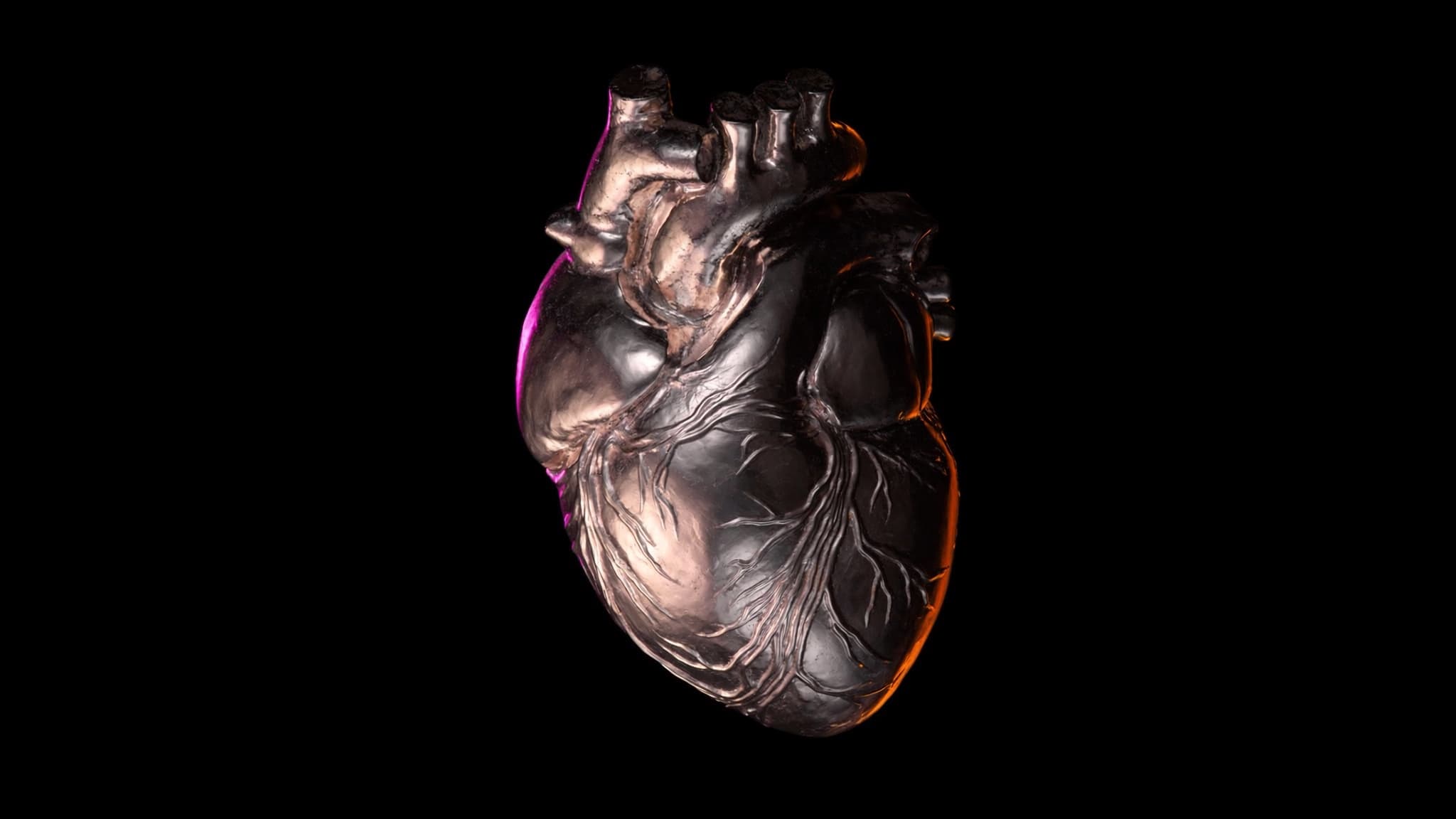 Corazón anatómico tallado como joya luminosa, iluminado en gradiente rosa naranja y púrpura sobre fondo negro